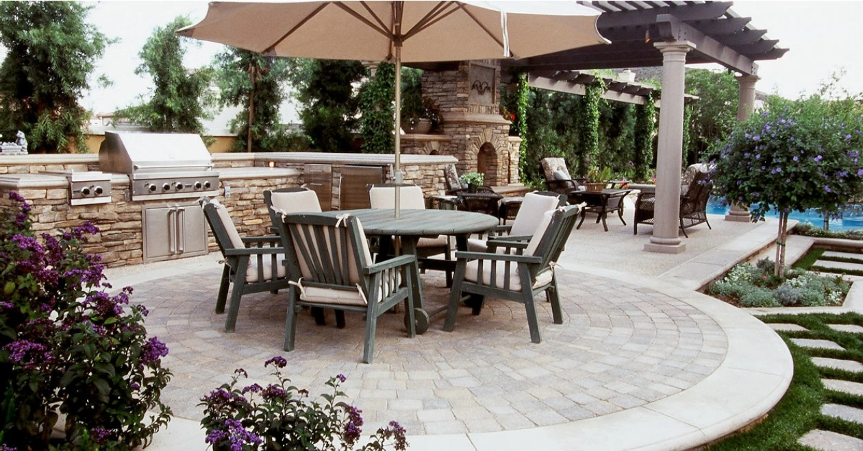 Custom concrete patio in Seagoville TX featuring outdoor kitchen, curved design with stone veneer, and pergola by Seagoville Concrete showcasing premium outdoor living space.